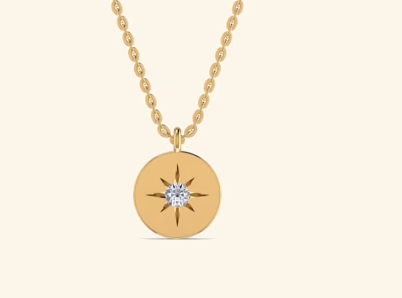 Round gold disc pendant with single star-cut diamond inset.
